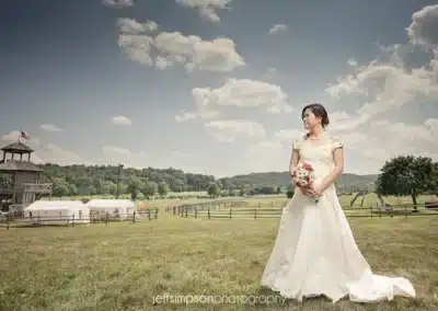 Bride on Great Meadow grounds with her wedding reception in background
